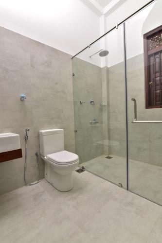 a bathroom with a toilet and a glass shower at Iain Lake Winds Villa in Galle
