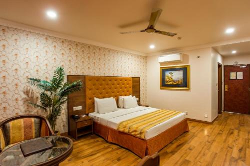 Schlafzimmer mit einem Bett und einem Deckenventilator in der Unterkunft The Grand Regency in Rajkot