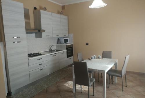 a kitchen with a table with chairs and a kitchen with white cabinets at "La ca` 'd Giaculin" -Casetta indipendente in Magliano Alpi