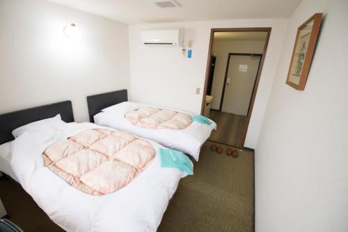two beds in a hotel room with pink blankets at Hikone Station Hotel in Hikone