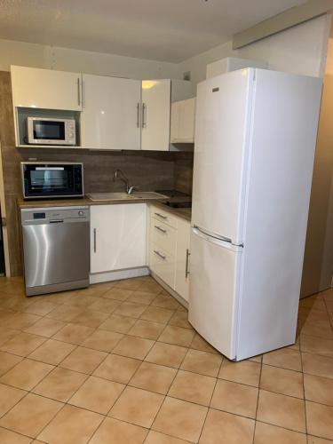 une cuisine avec des armoires blanches et un réfrigérateur blanc dans l'établissement Appartement Bord de mer, à La Londe-les-Maures