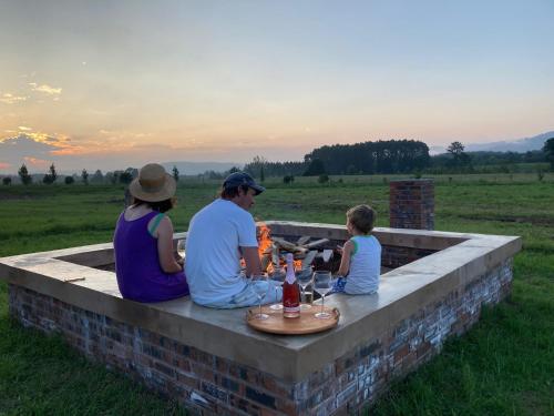 una familia sentada alrededor de una hoguera viendo la puesta de sol en Belvidere Country Estate, en Yarrow