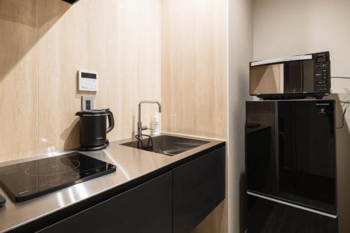 a small kitchen with a sink and a microwave at GRAND BASE Hakata Premium in Fukuoka