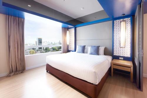 
a bedroom with a large bed and a large window at The Quarter Hualamphong by UHG - SHA Extra Plus in Bangkok
