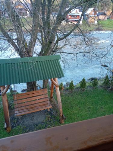 a park bench with a green roof next to a tree at Yablunevyi Tsvit in Yaremche