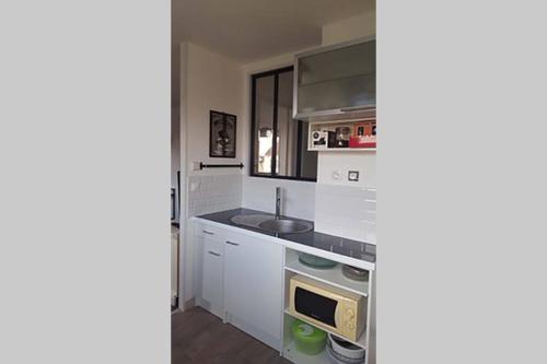 une cuisine avec des armoires blanches et un évier dans l'établissement Duplex 1 station tramway aéroport Paris-Orly, à Athis-Mons