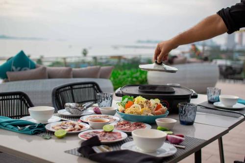 a person cooking food on a table with a grill at Seaphere Pattaya Hotel by Elite Suites in Na Jomtien