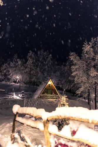 a cabin in the snow at night at Etno Village Dolina Sreće in Vitez