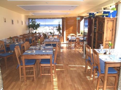 a restaurant with blue tables and chairs and a large window at Le Vieux Chien Noir in Évran