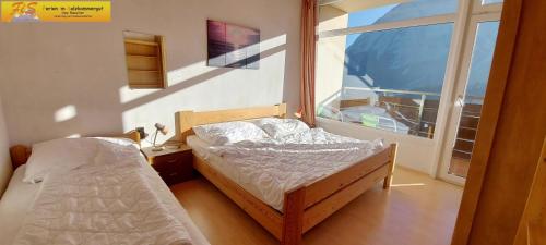 1 Schlafzimmer mit 2 Betten und einem großen Fenster in der Unterkunft Apartment Grimmingsuite by FiS - Fun in Styria in Tauplitz