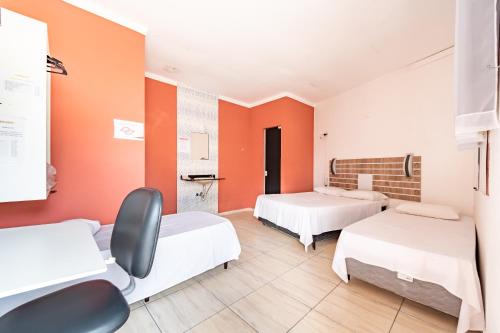 Habitación con 2 camas y paredes de color naranja. en Hotel Campolim en Sorocaba