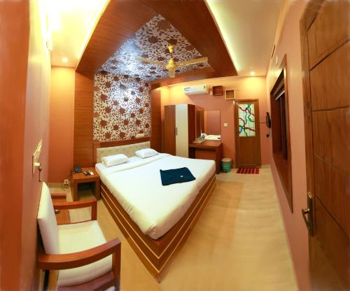 a bedroom with a bed and a chair in a room at Gateway Airport Hotel in Kannur