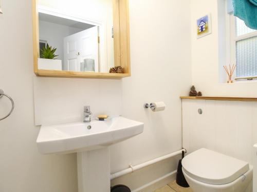 y baño con lavabo, aseo y espejo. en Castle Cove View, en Weymouth