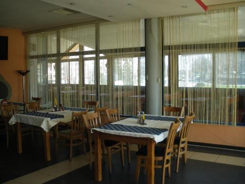 comedor con 2 mesas, sillas y ventanas en Brani Family Hotel, en Ruse