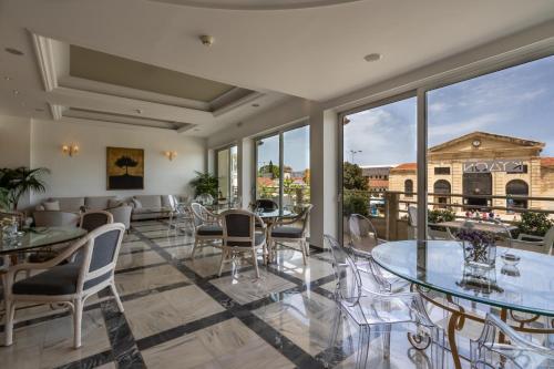 a dining room with tables and chairs and windows at Kydon The Heart City Hotel in Chania Town