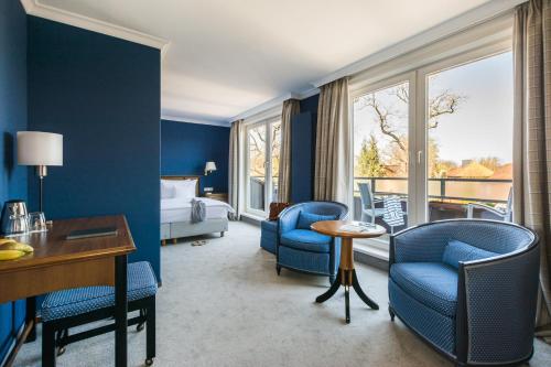 ein Hotelzimmer mit einem Bett, einem Schreibtisch und Stühlen in der Unterkunft Niemeyers Romantik Posthotel in Faßberg