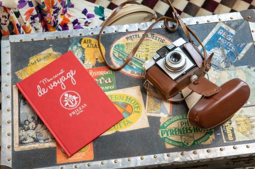 a suitcase with a passport and a camera on it at Hotel Phileas Lazare & Spa - Opera in Paris