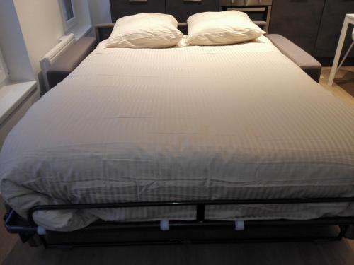un letto con lenzuola e cuscini bianchi di DELARNOR - Confort et sérénité a Saint-Quentin