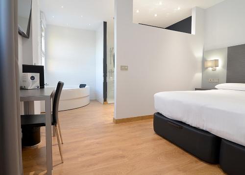 a bedroom with a bed and a desk and a bathroom at UVE Alcobendas in Alcobendas