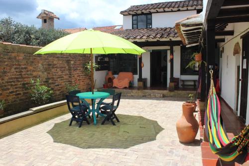 een groene tafel en stoelen onder een gele paraplu bij Hostal Rana in Villa de Leyva