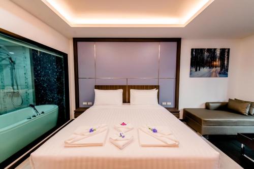 a bedroom with a bed and a bathtub and a bed with two towels at The Proud Hotel Pattaya - SHA Certified in Pattaya North