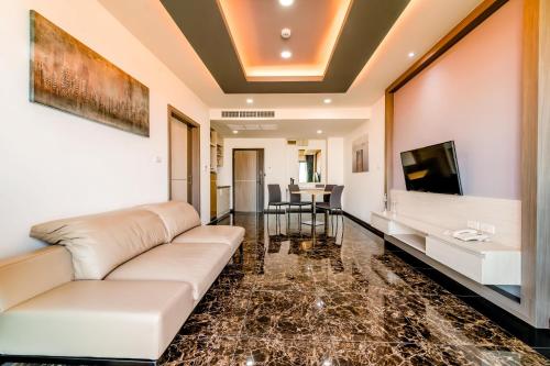 a living room with a couch and a tv at The Proud Hotel Pattaya - SHA Certified in Pattaya North