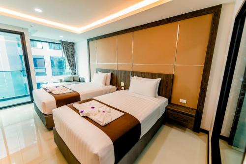 a hotel room with two beds and a window at The Proud Hotel Pattaya - SHA Certified in Pattaya North