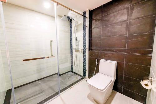 a bathroom with a toilet and a glass shower at The Proud Hotel Pattaya - SHA Certified in Pattaya North