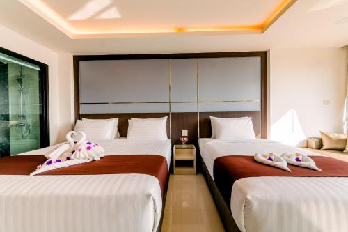 a hotel room with two beds with towels on them at The Proud Hotel Pattaya - SHA Certified in Pattaya North