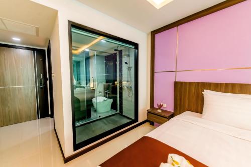 a bedroom with a bed and a glass shower at The Proud Hotel Pattaya - SHA Certified in Pattaya North
