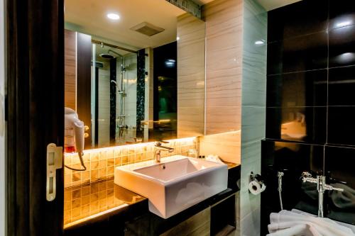 a bathroom with a sink and a mirror at The Proud Hotel Pattaya - SHA Certified in Pattaya North