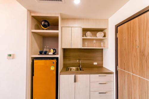 a kitchen with a yellow refrigerator and a sink at The Proud Hotel Pattaya - SHA Certified in Pattaya North