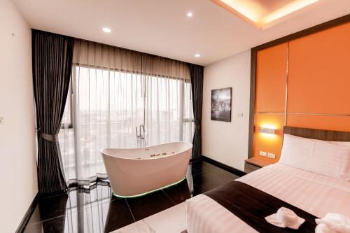 a bedroom with a bed and a bath tub next to a window at The Proud Hotel Pattaya - SHA Certified in Pattaya North