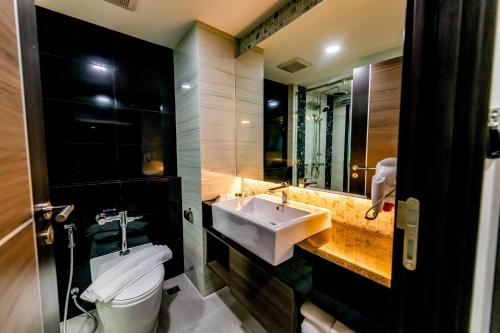 a bathroom with a sink and a toilet and a mirror at The Proud Hotel Pattaya - SHA Certified in Pattaya North