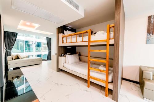 a bedroom with bunk beds and a living room at The Proud Hotel Pattaya - SHA Certified in Pattaya North