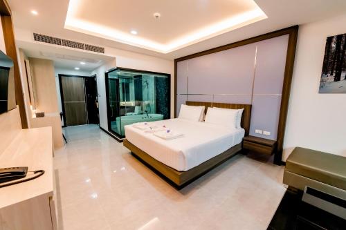 a bedroom with a large white bed and a bathroom at The Proud Hotel Pattaya - SHA Certified in Pattaya North