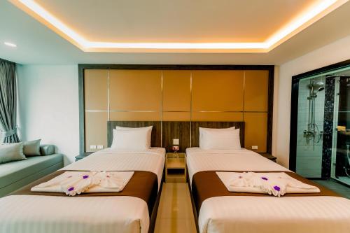 a bedroom with two beds and a couch at The Proud Hotel Pattaya - SHA Certified in Pattaya North