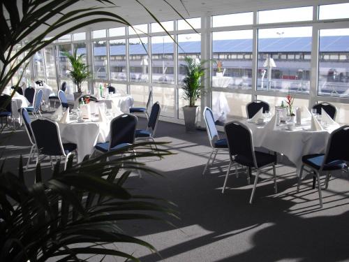 Pokój z białymi stołami, krzesłami i oknami w obiekcie Hotel Motodrom w mieście Hockenheim