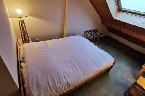 a bed in a room with a lamp and a window at Ravissant appart proche suisse et pistes de ski familiales in Les Fourgs