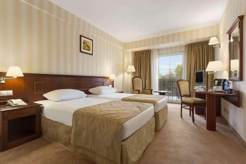 a hotel room with two beds and a television at Ramada Hotel & Suites by Wyndham Bucharest North in Bucharest