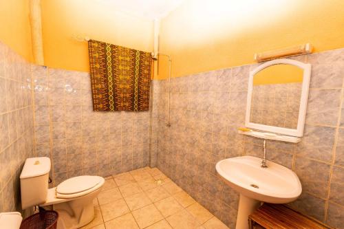 y baño con aseo, lavabo y espejo. en Auberge Africa Thiossane, en Saly Portudal