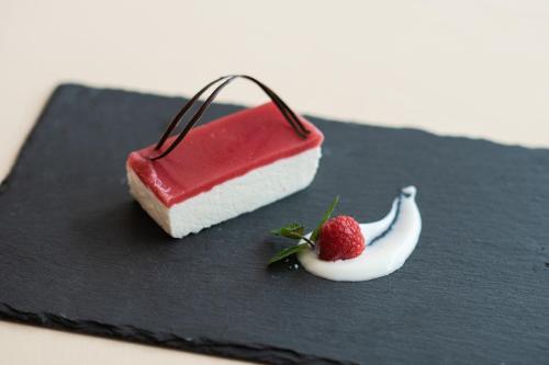 a piece of cake and a strawberry on a black plate at Hotel Zum Mohren in Resia
