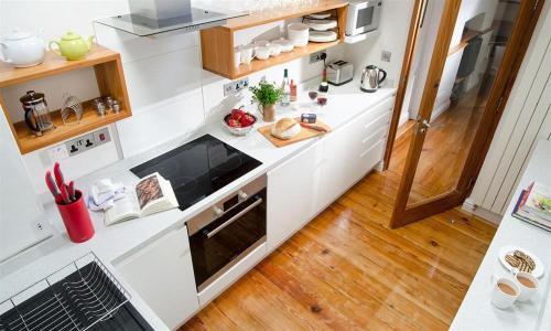 a kitchen with white counters and wooden floors at The Stable At Oakbank in Elterwater