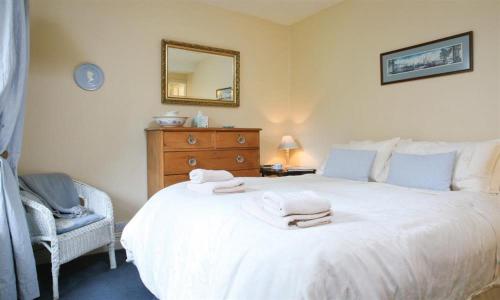 a bedroom with a white bed with a mirror and a chair at Syke Villa in Troutbeck