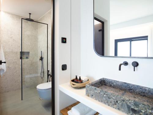 a bathroom with a sink and a toilet and a mirror at Epic Mykonos in Mikonos