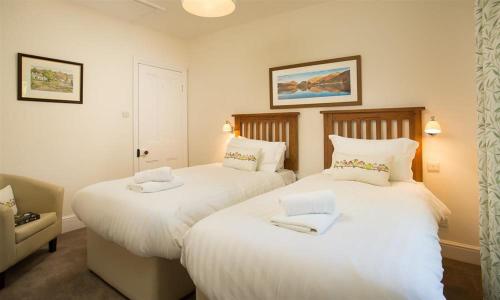 two beds in a hotel room with white sheets at Oxen Fell Cottage in Little Langdale