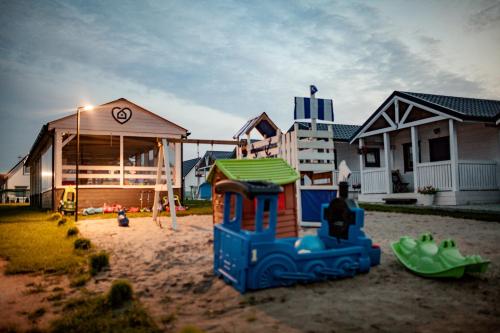 a playground in the sand in front of a house at Krysiakowe Chatki in Gąski