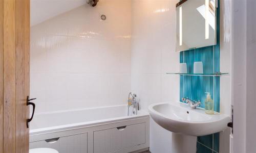 ein weißes Badezimmer mit einem Waschbecken und einem Spiegel in der Unterkunft Nest Barn in Keswick