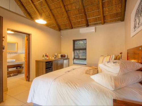 1 dormitorio con 1 cama blanca grande y baño en The Den at Kruger 3479 en Marloth Park