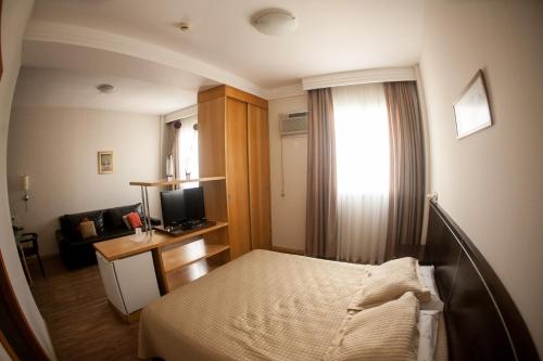 a hotel room with a bed and a television at Unidade no Hotel Piemonte - Vila da Serra in Macacos